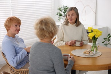 Photo of Friendship. Senior women enjoying hot drinks at table indoors