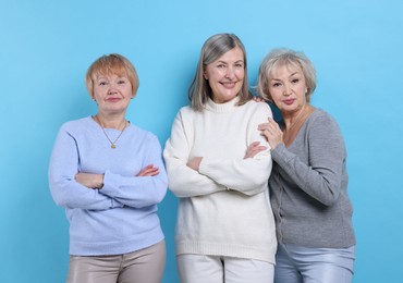 Friendship. Portrait of senior women on light blue background