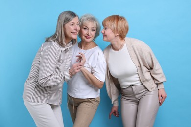 Friendship. Portrait of senior women on light blue background