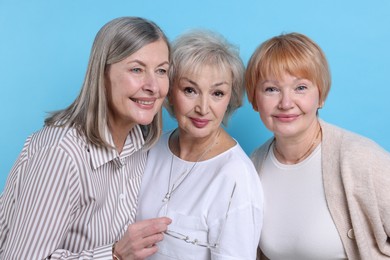 Friendship. Portrait of senior women on light blue background