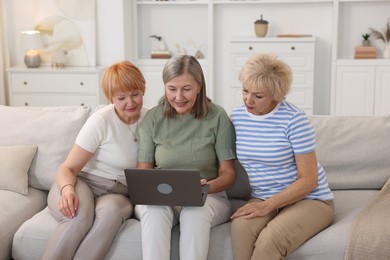 Friendship. Senior women watching something on laptop at home