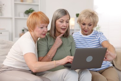 Friendship. Senior women watching something on laptop at home