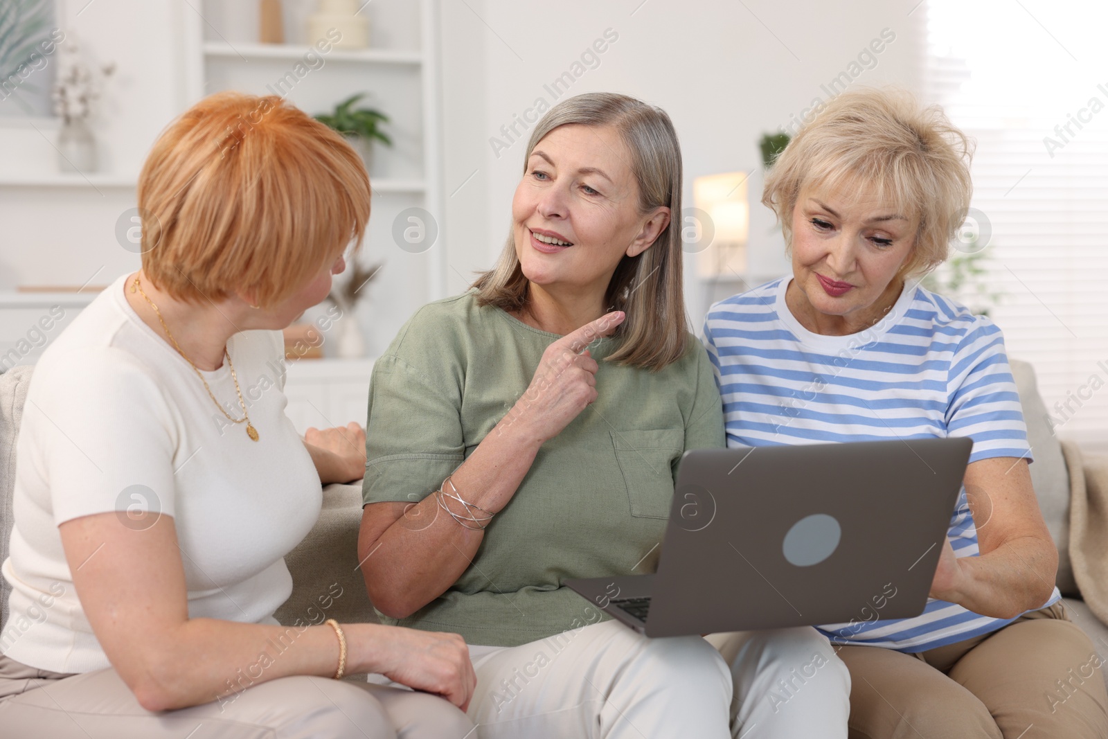 Photo of Friendship. Senior women watching something on laptop at home