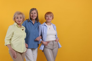 Photo of Friendship. Portrait of senior women on orange background, space for text