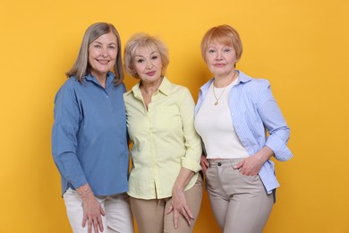 Friendship. Portrait of senior women on orange background