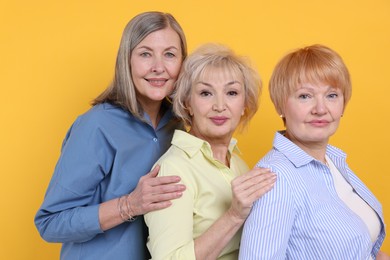 Friendship. Portrait of senior women on orange background