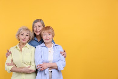 Photo of Friendship. Portrait of senior women on orange background, space for text