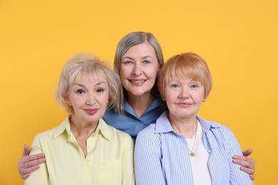 Friendship. Portrait of senior women on orange background