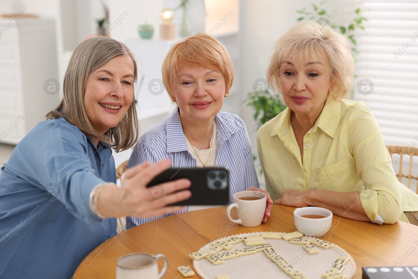 Photo of Friendship. Senior women taking selfie at table indoors