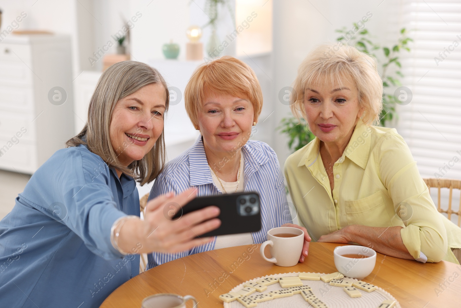 Photo of Friendship. Senior women taking selfie at table indoors