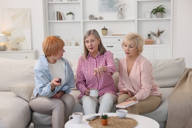 Friendship. Senior women watching tv on sofa at home