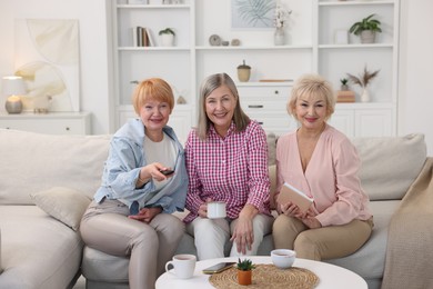 Friendship. Senior women watching tv on sofa at home