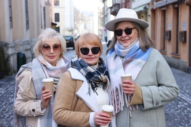 Photo of Friendship. Senior women enjoying hot drinks on city street