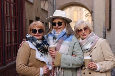 Friendship. Senior women enjoying hot drinks on city street