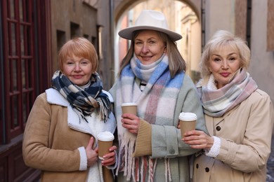 Friendship. Senior women enjoying hot drinks on city street