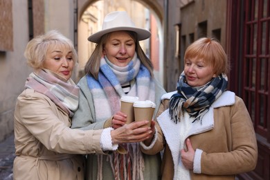 Photo of Friendship. Senior women enjoying hot drinks on city street