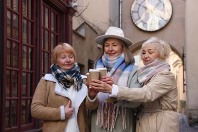 Friendship. Senior women enjoying hot drinks on city street