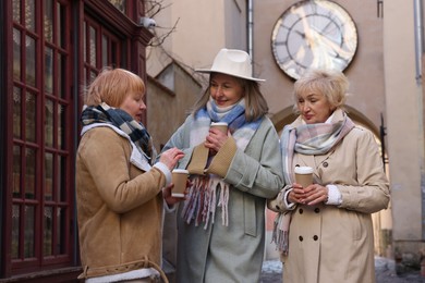 Photo of Friendship. Senior women enjoying hot drinks on city street