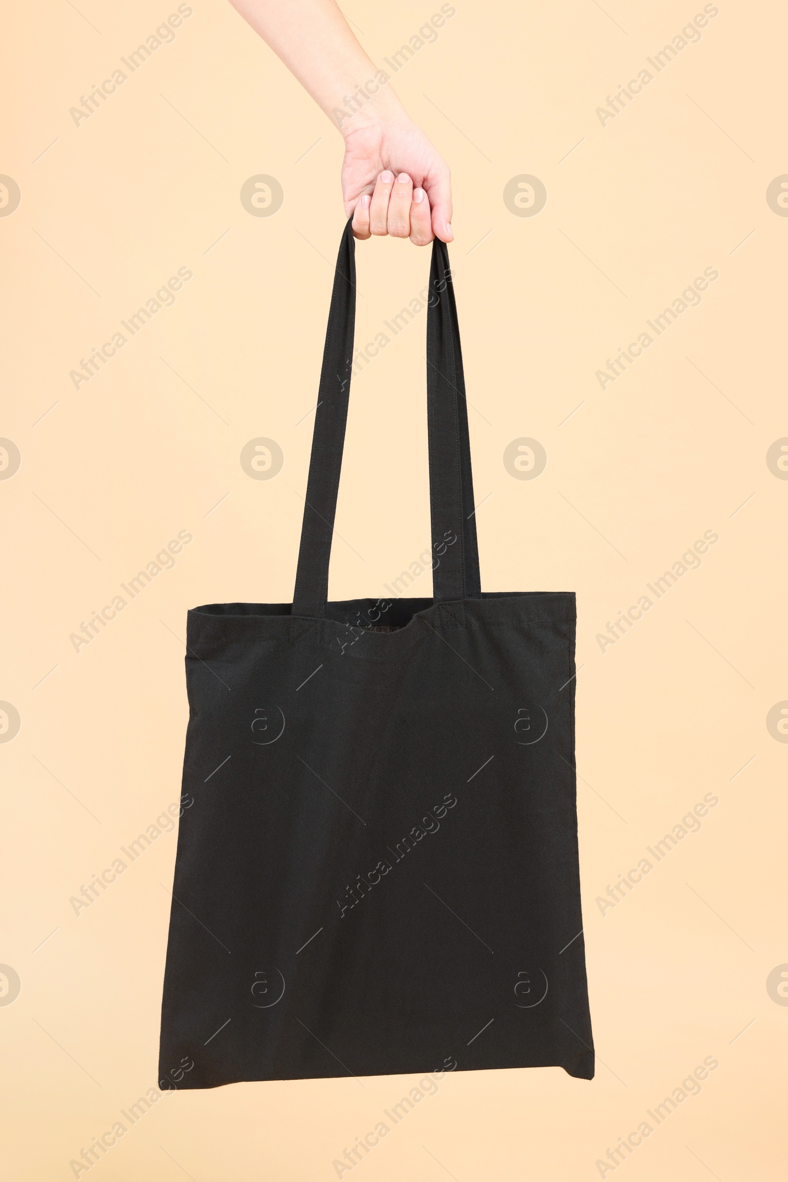 Photo of Woman with blank black shopper bag on color background, closeup. Mockup for design