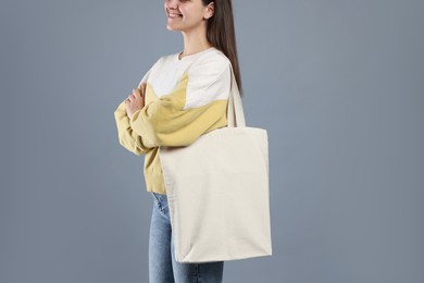 Photo of Woman with blank shopper bag on grey background, closeup. Mockup for design