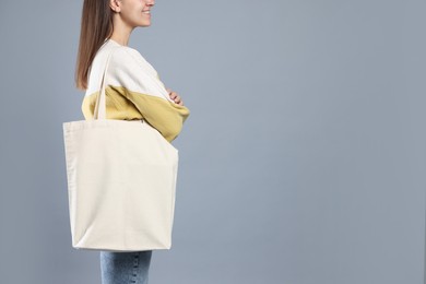 Photo of Woman with blank shopper bag on grey background, closeup. Mockup for design