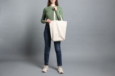 Woman with blank shopper bag on grey background, closeup. Mockup for design