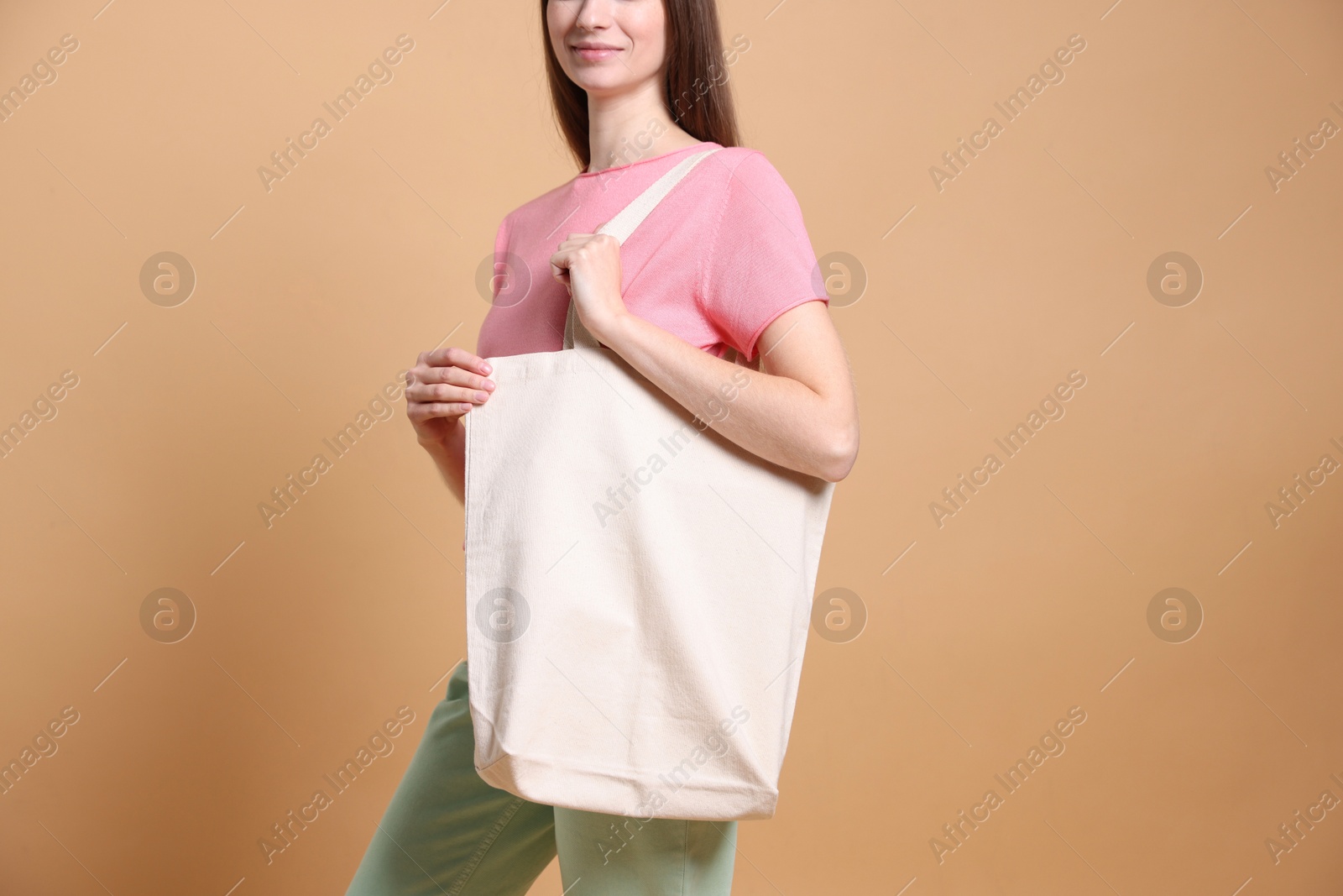 Photo of Woman with blank shopper bag on beige background, closeup. Mockup for design