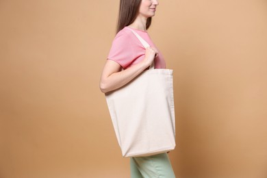 Photo of Woman with blank shopper bag on beige background, closeup. Mockup for design