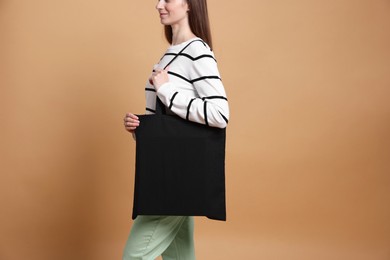 Photo of Woman with blank shopper bag on beige background, closeup. Mockup for design