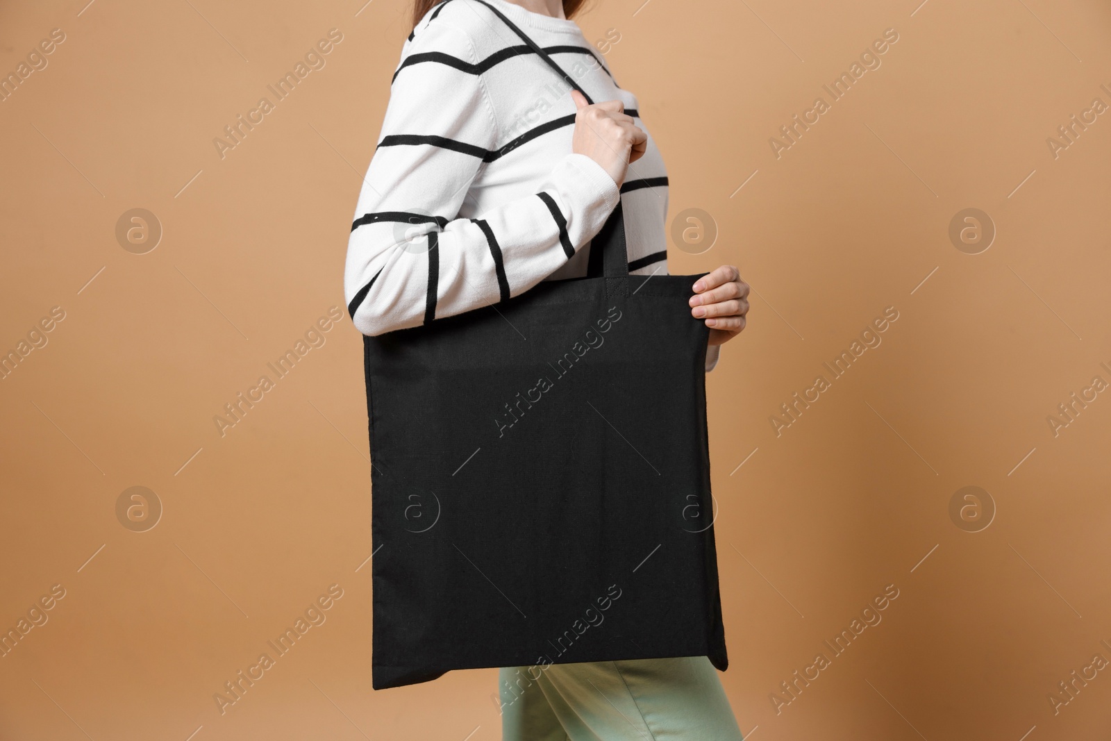 Photo of Woman with blank shopper bag on beige background, closeup. Mockup for design