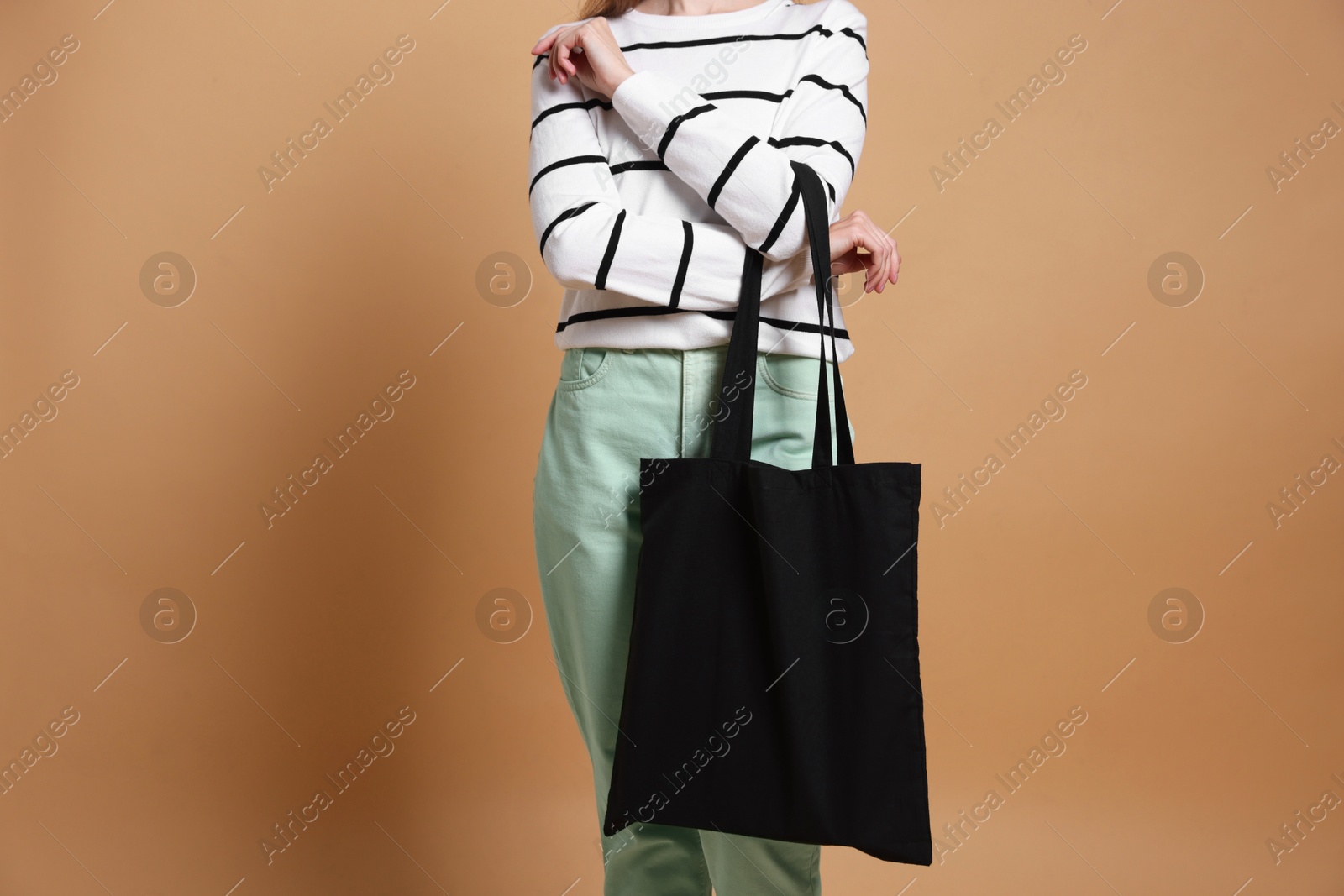 Photo of Woman with blank shopper bag on beige background, closeup. Mockup for design