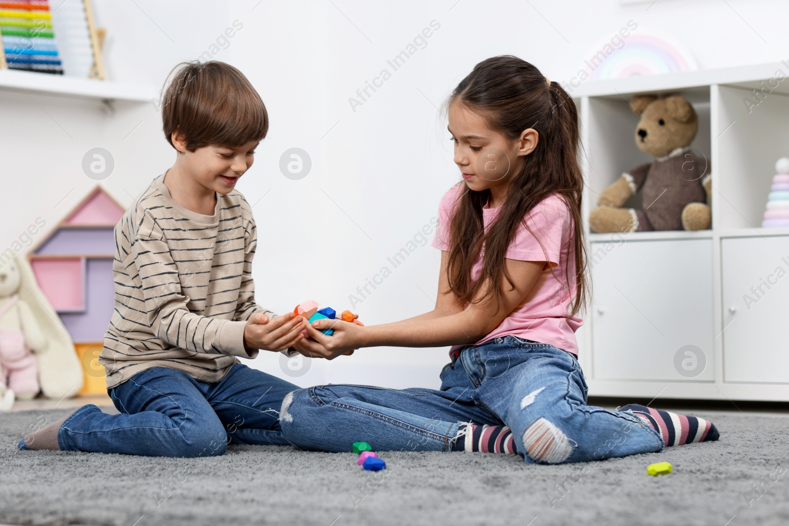 Photo of Children playing with balancing stones on floor indoors