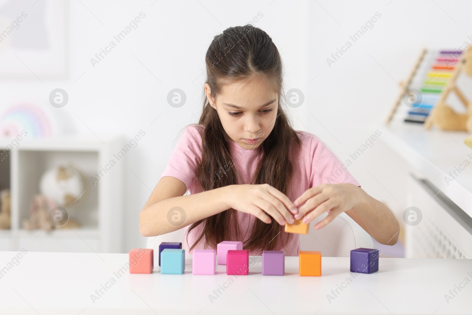 Photo of Girl with colorful cubes at table indoors