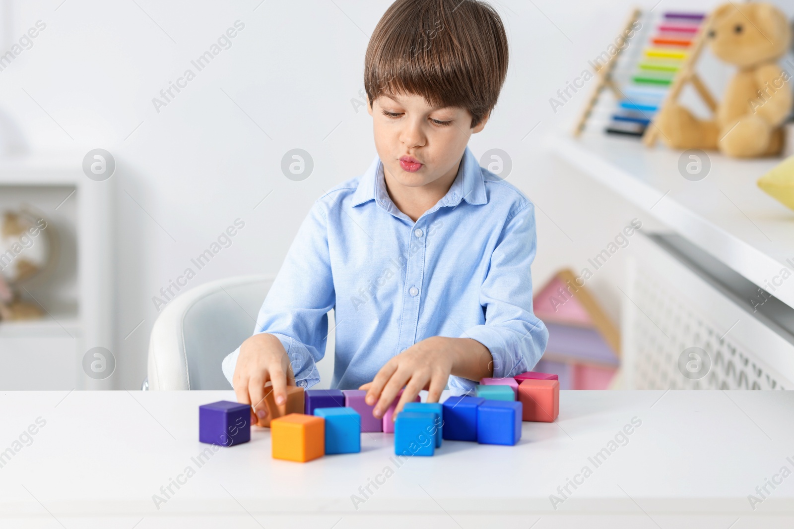 Photo of Boy with colorful cubes at table indoors