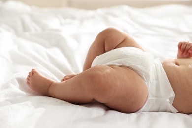 Photo of Cute little baby in diaper on bed, closeup