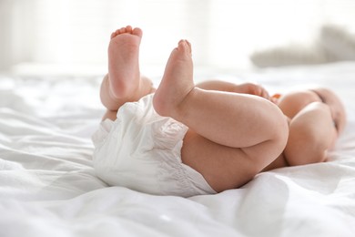 Photo of Cute little baby in diaper on bed indoors, selective focus