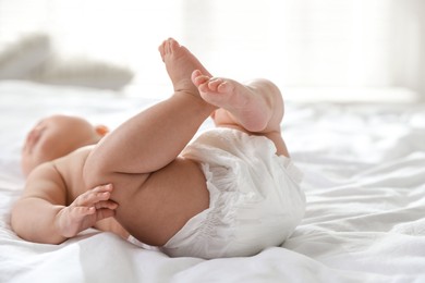 Photo of Cute little baby in diaper on bed indoors, selective focus