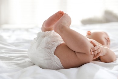 Photo of Cute little baby in diaper on bed indoors, selective focus