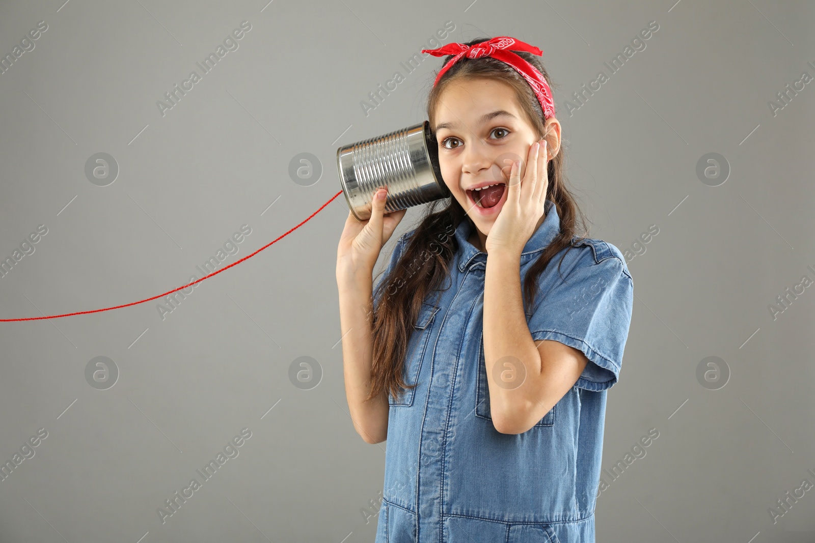 Photo of Girl using tin can telephone on gray background