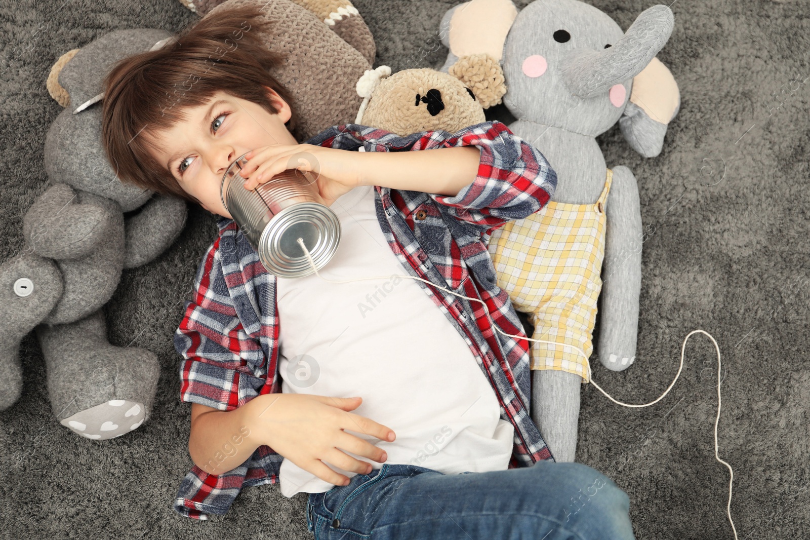 Photo of Boy using tin can telephone on gray rug, top view