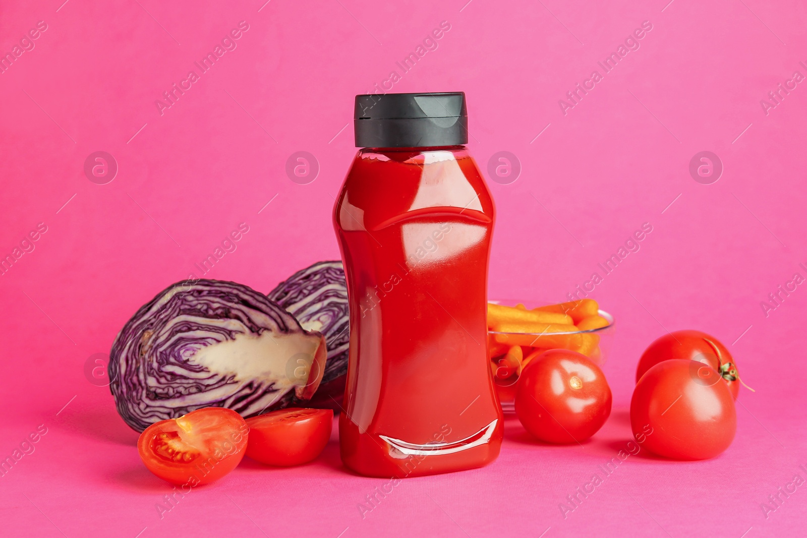 Photo of Tasty ketchup and vegetables on pink background