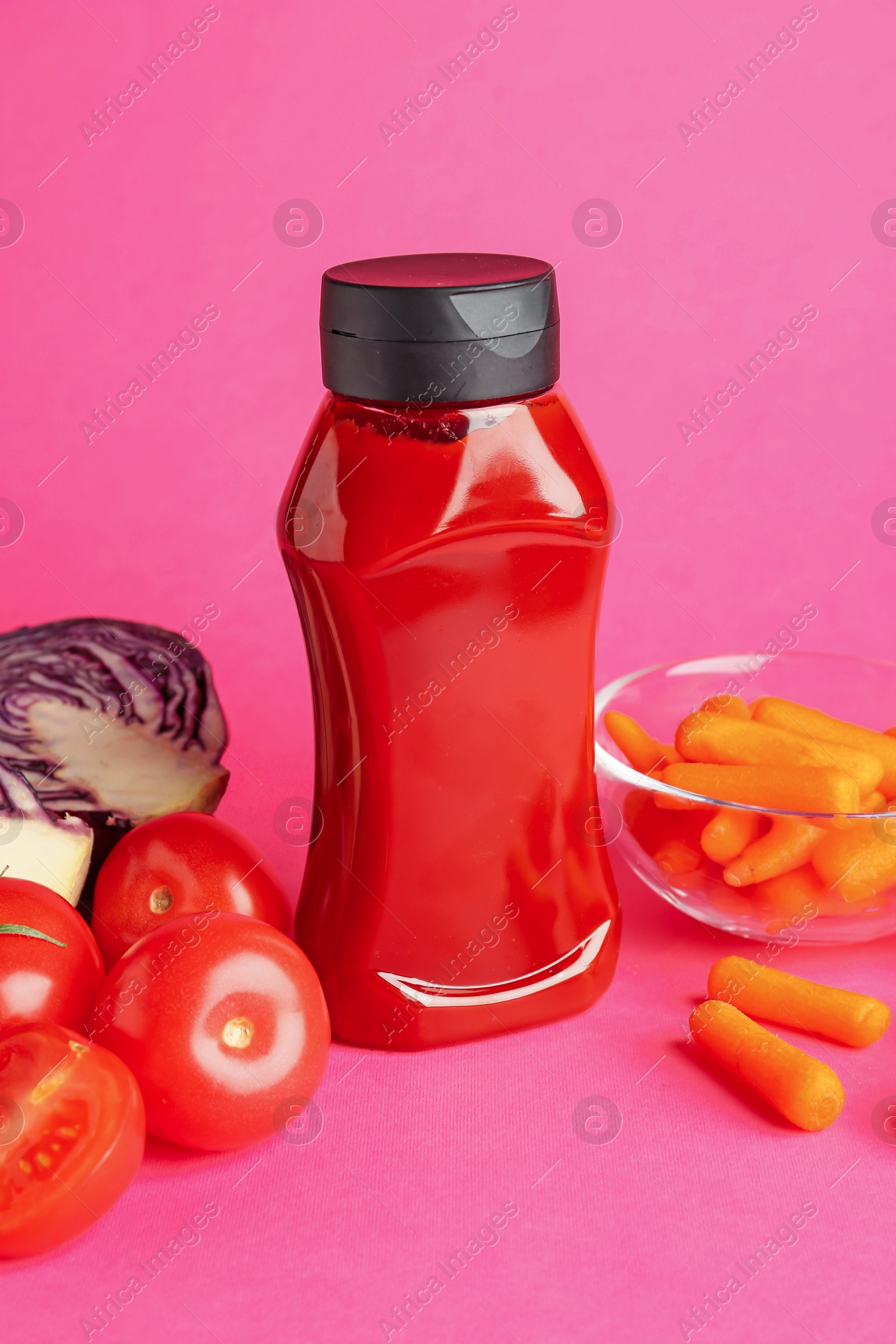 Photo of Tasty ketchup and vegetables on pink background