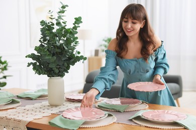 Woman setting table for dinner at home