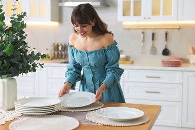 Photo of Woman setting table for dinner at home