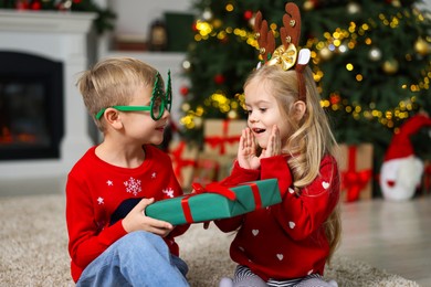 Little boy giving Christmas gift to girl at home