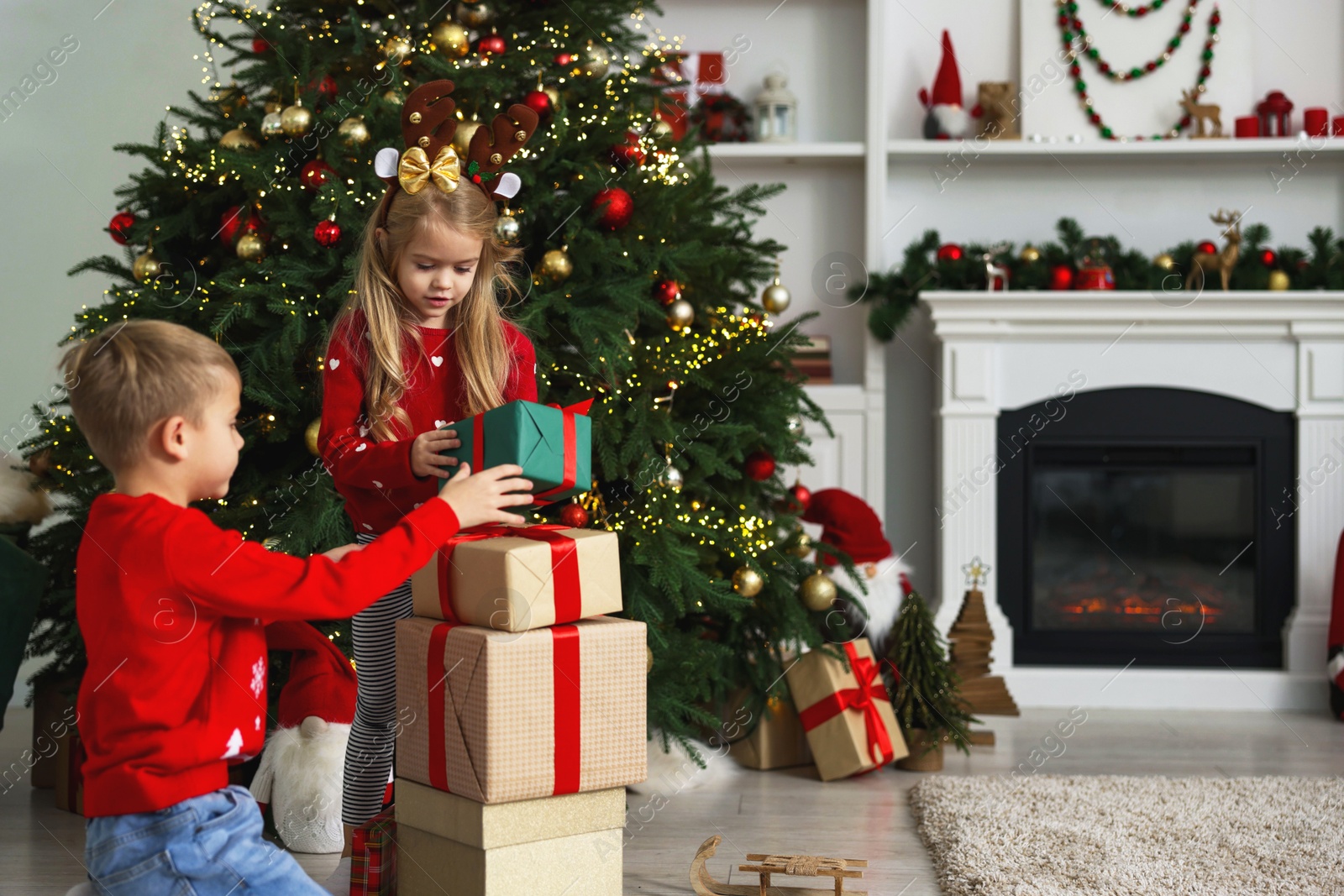 Photo of Little children with gifts near Christmas tree at home. Space for text