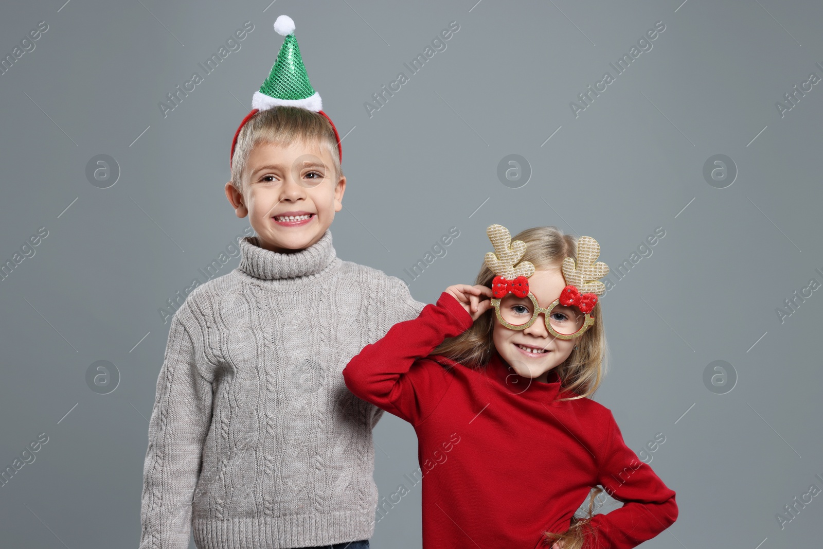 Photo of Funny children in Christmas accessories on grey background