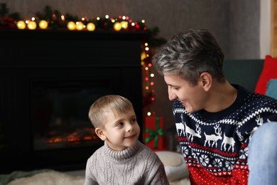 Dad and son near decorated fireplace at home. Christmas season