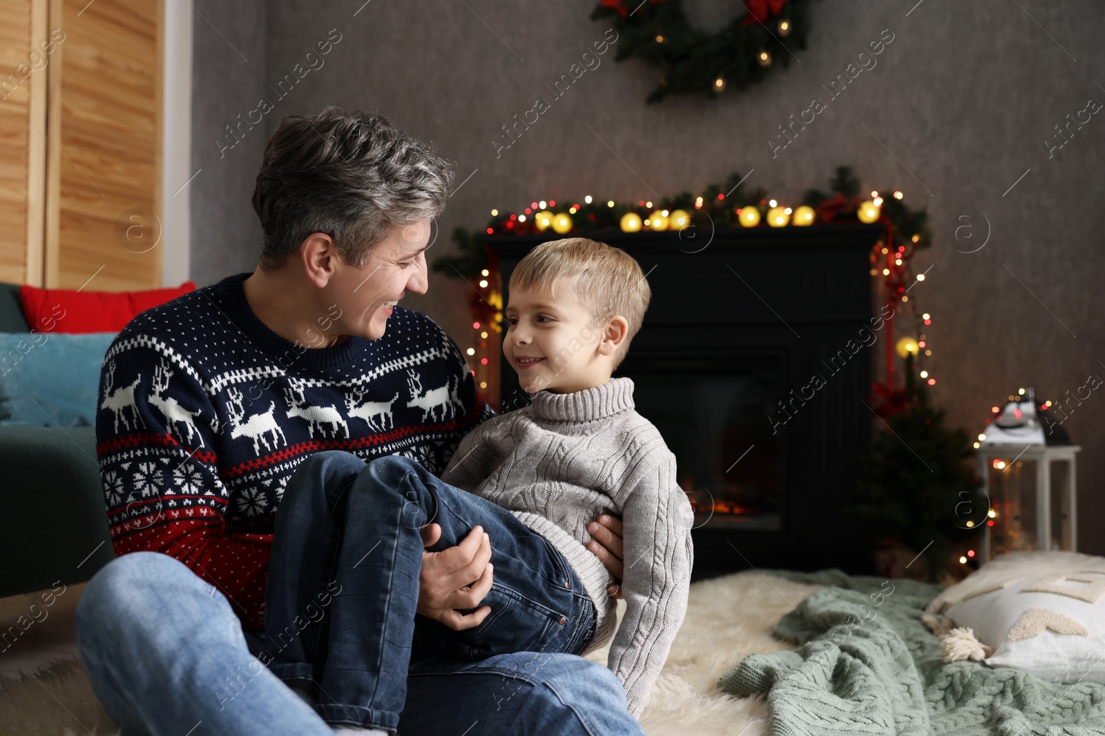 Photo of Dad and son near decorated fireplace at home. Christmas season