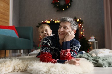 Photo of Dad and son near decorated fireplace at home. Christmas season